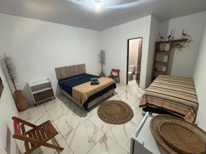 a bedroom with two beds and two chairs in it at Cajuí da Vila Atins in Atins