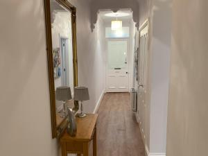 a hallway with a mirror and a table with a lamp at 2 Windsor House in Keswick