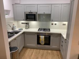 a kitchen with white cabinets and a stove top oven at 2 Windsor House in Keswick