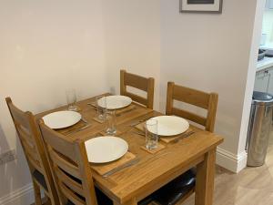 a wooden table with plates and wine glasses on it at 2 Windsor House in Keswick