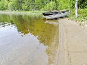 a boat sitting on the shore of a body of water at Holiday Home Honkaniemi by Interhome in Rasivaara