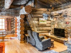 a log cabin living room with a fireplace and a chair at Holiday Home Suutarinkolo by Interhome in Levi