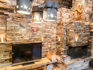 a living room with a tv and a stone wall at Holiday Home Suutarinkolo by Interhome in Levi +19 photos