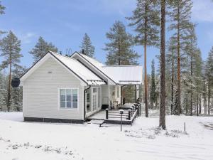 a small white house with a porch in the snow at Holiday Home Teppolan rinne by Interhome in Salla