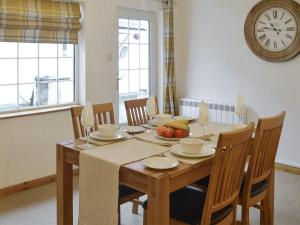 a dining room table with chairs and a clock on the wall at Clover Cottage in Keswick