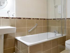 a bathroom with a bath tub and a toilet at Clover Cottage in Keswick
