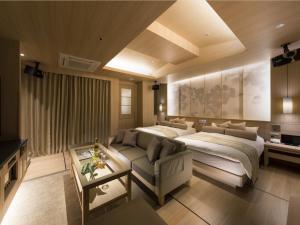 a bedroom with a bed and a couch and a table at HOTEL SWEET SEASON-L in Ginan