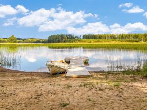 a small boat sitting next to a dock on a lake at Holiday Home Kaisla by Interhome in Pertunmaa