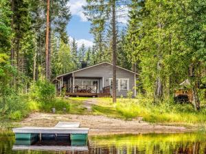 a cabin in the woods next to a body of water at Holiday Home Kaisla by Interhome in Pertunmaa +17 photos