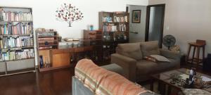 a living room with a couch and book shelves at Quarto Suíte Amora in Atibaia