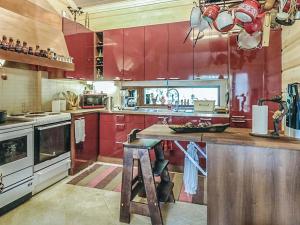a kitchen with red cabinets and a counter with a stool at Holiday Home Ruuhikari by Interhome in Ulvila