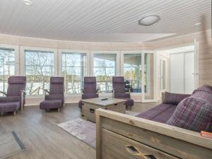 a living room with a couch and chairs and windows at Holiday Home Paula by Interhome in Lihavanpää