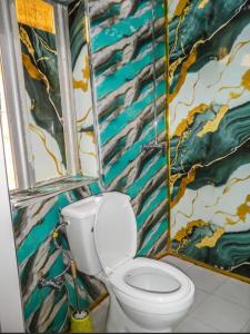 a bathroom with a toilet and a colorful wall at Hôtel Ami Bamba in Mbour +30 photos