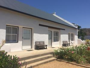a white house with two benches in front of it at Sempurna Estate in McGregor