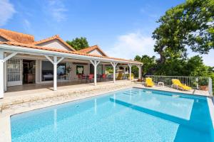 a swimming pool in front of a house at Villa Lueurs du Rocher in Le Diamant