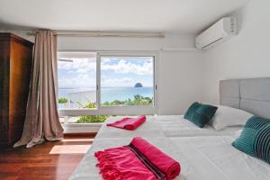 a bedroom with a bed with a large window at Villa Lueurs du Rocher in Le Diamant +30 photos