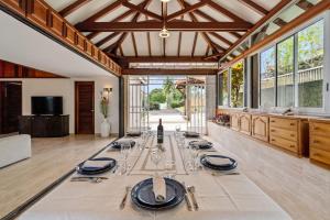 a dining room with a long table with glasses at Villa Lueurs du Rocher in Le Diamant