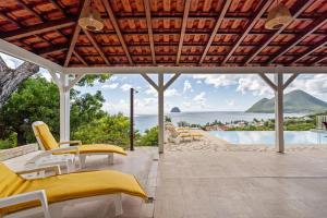 an outdoor patio with yellow chairs and a view of the ocean at Villa Lueurs du Rocher in Le Diamant