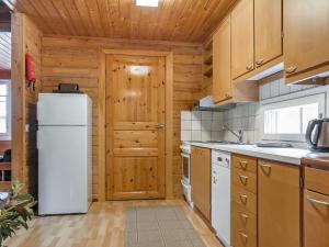 a kitchen with a white refrigerator and wooden cabinets at Holiday Home Lomamaja 2 by Interhome in Raattama