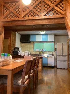 a kitchen with a wooden table and a refrigerator at コテージ　マリーゴールド in Nasu-yumoto