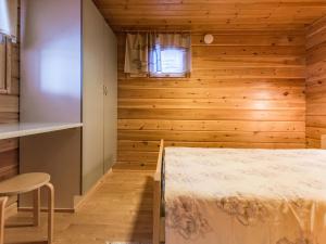 a bedroom with a bed and a wooden wall at Holiday Home Lomapesä 2b by Interhome in Kotila +6 photos