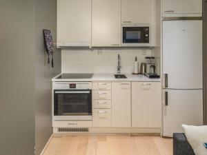 a kitchen with white cabinets and a refrigerator at Holiday Home Levin stara c11 by Interhome in Levi