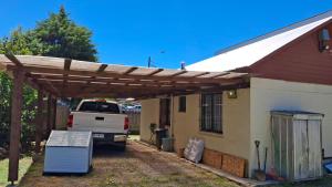 a truck parked under a wooden pergola next to a house at Casa Huedhued in Villarrica