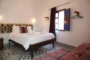 una camera da letto con un letto bianco con una finestra di Riad Imndi a Marrakech