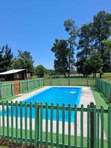 a fence next to a blue swimming pool at Paraíso Rustico 3 in Curacautín
