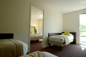 a bedroom with two beds and a mirror at The Originals City, Hôtel La Verriaire, Cholet Sud in La Verrie