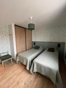 a bedroom with two beds and a table and a lamp at La GOELETTE in Quend-Plage