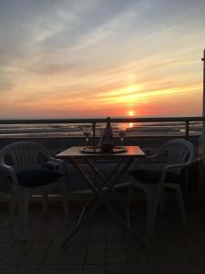 a table and chairs on a balcony with a sunset at La GOELETTE in Quend-Plage