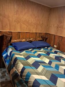 a bed with blue and white sheets and blue pillows at Paraíso Rustico 1 in Curacautín