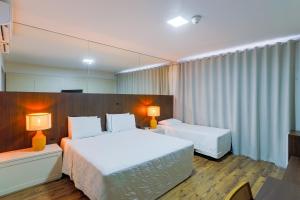 a hotel room with two beds and two lamps at Alven Hotel by Slaviero Hotéis in Joinville