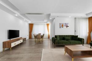 a living room with a green couch and a television at River Park Residence Lara in Antalya