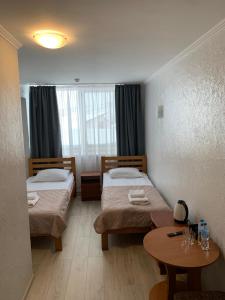 ein Hotelzimmer mit zwei Betten und einem Tisch in der Unterkunft Готель "Дубно" in Dubno