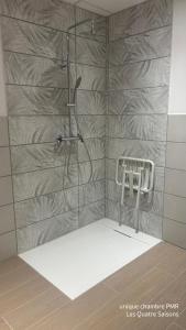 a shower in a bathroom with a gray tiled wall at Hôtel Les Quatre Saisons in Dullin +42 photos