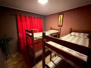 a room with two bunk beds and red curtains at Pousada Complexo Girassol in Dourados