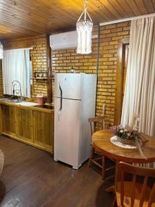 a kitchen with a white refrigerator and a table at Sitio Meu Refúgio Paracuru in Paracuru
