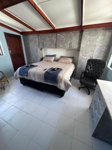 a bedroom with a bed and a black chair at 52 Maroela street in Mossel Bay