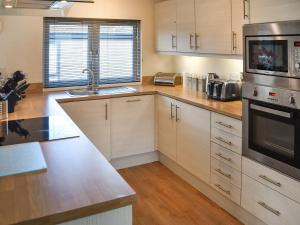 a kitchen with white cabinets and stainless steel appliances at Highview in North Walsham +12 photos