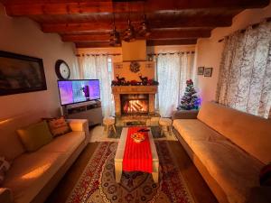 a living room with a fireplace and a christmas tree at Vila Korcari Dardhe in Dardhë
