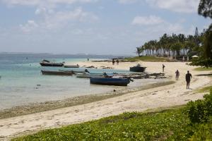 people walking on a beach with boats in the water at Beny SeaBeach Residence in Belle Mare