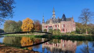 a large castle with a bridge over a river at Erve Lindehof in Lochem
