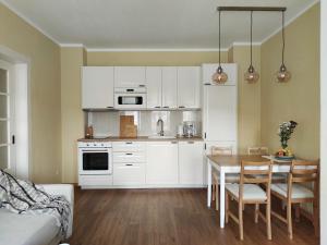 a kitchen with white cabinets and a table with chairs at Eine gemütliche Ferienwohnung in Kurort Gohrisch