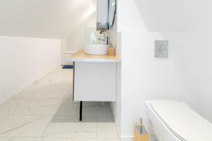 a white bathroom with a sink and a tub at La perle de Montargis - Charmant T2 in Montargis