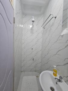 a white bathroom with a shower and a sink at Upscale homes in Ongata Rongai 