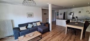 a living room with a blue couch and a table at Le vitrail d'Arcachon - Appt Spacieux Terrasse Ménage draps inclus in Arcachon +19 photos