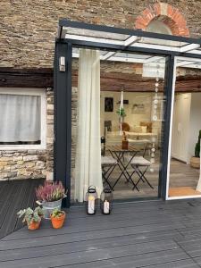 an open sliding glass door on a patio with plants at Charmant Studio in Le Breuil-en-Bessin +14 photos