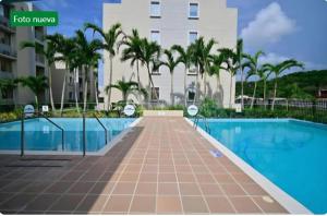 a swimming pool with palm trees and a building at Capriella,Cartagena in Cartagena de Indias